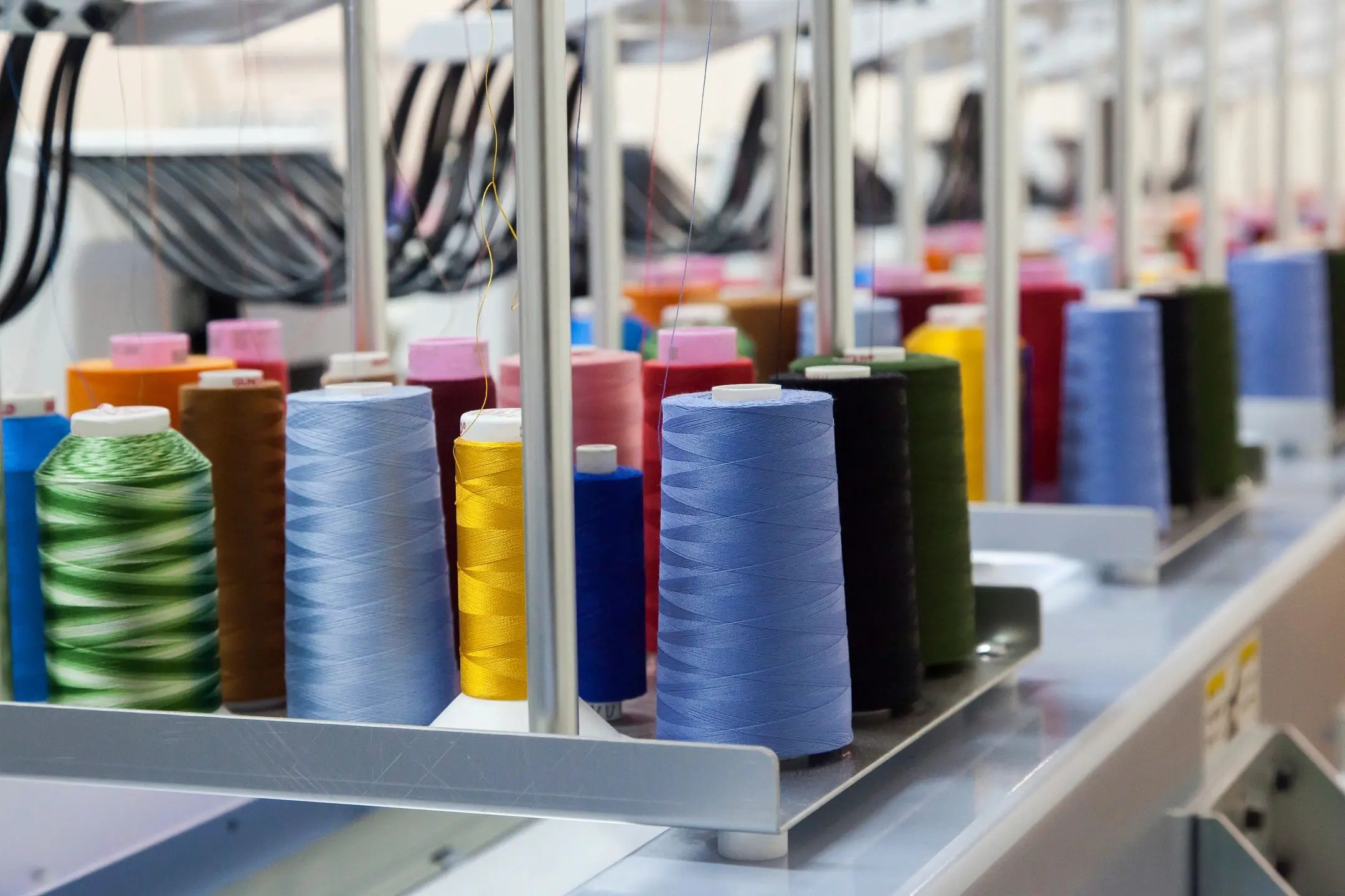 A row of spools of thread on a machine.